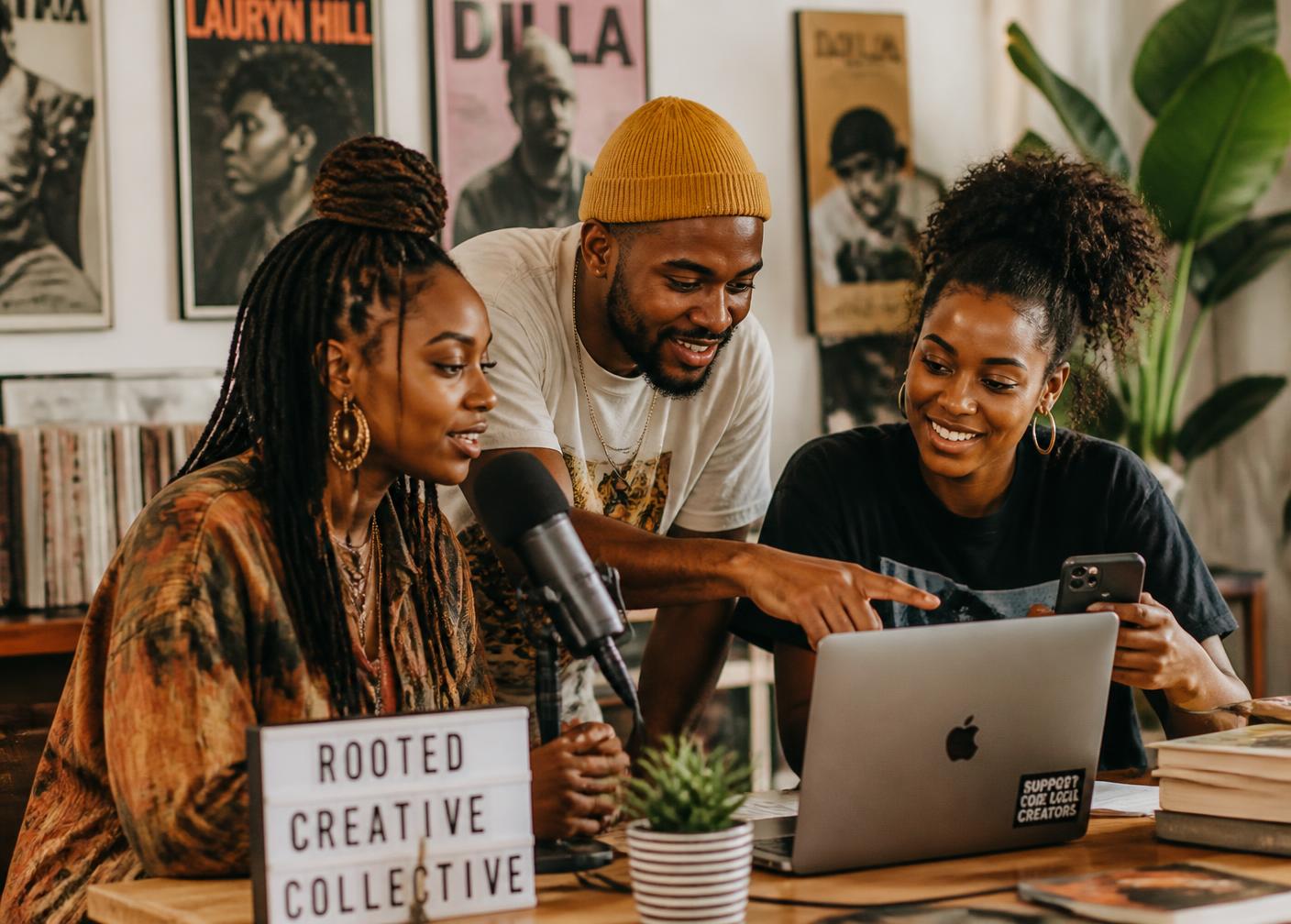 Black creators and podcasters collaborating around a microphone and laptop